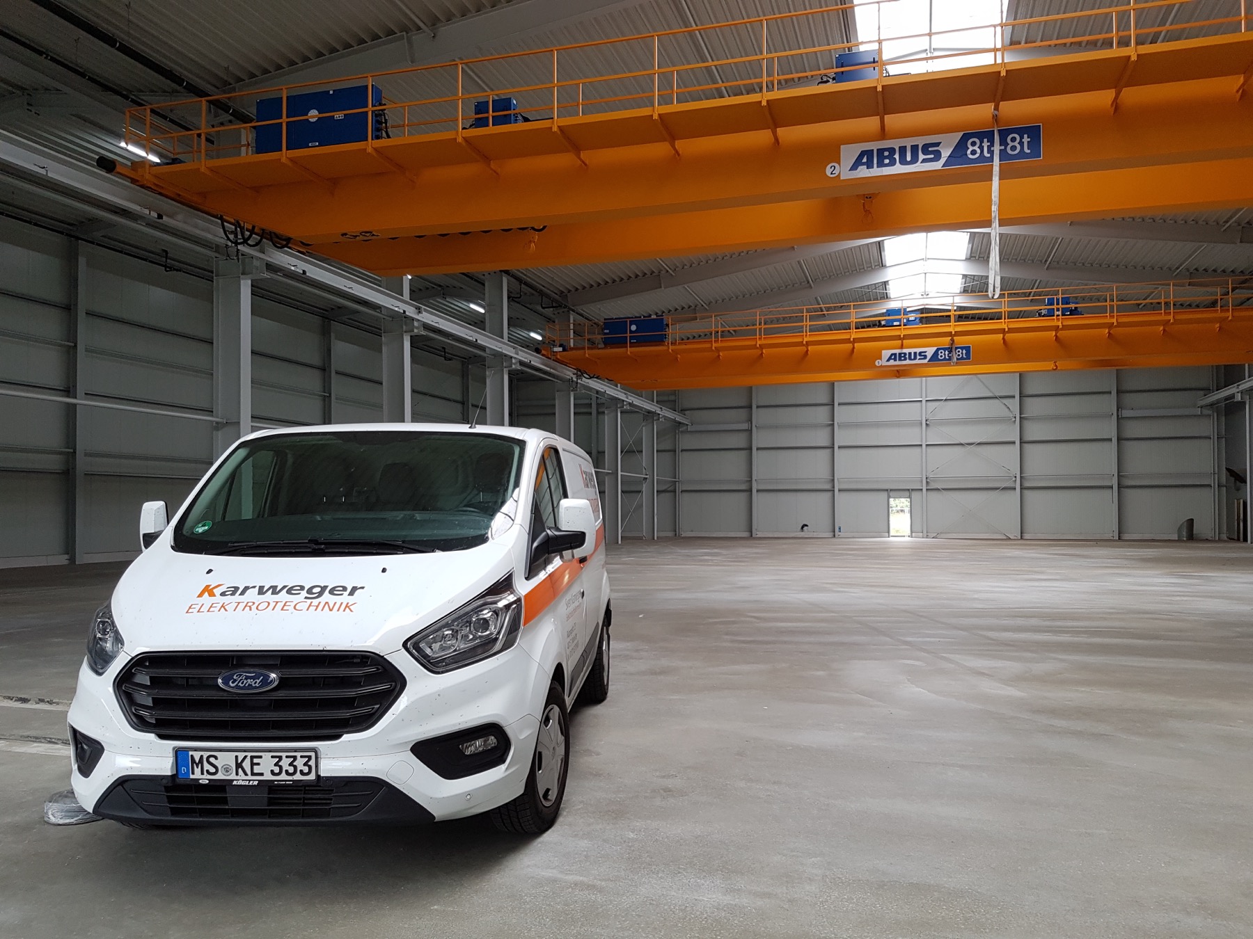 KARWEGER Elektrotechnik — Firmenwagen in Industriehalle, Krananlage im Hintergrund